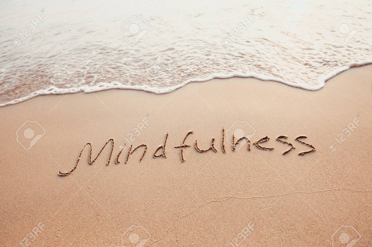 mindfulness concept, mindful living, text written on the sand of beach